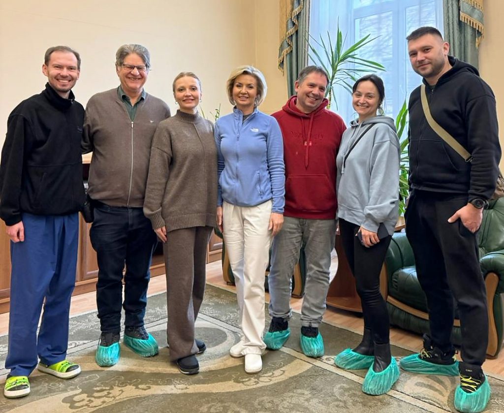 Gruppenfoto im Büroraum einer Klinik: m, m, f, f, m, f, m

Gelöste Atmosphäre. Einige tragen Plastiküberzüge an den Straßenschuhen